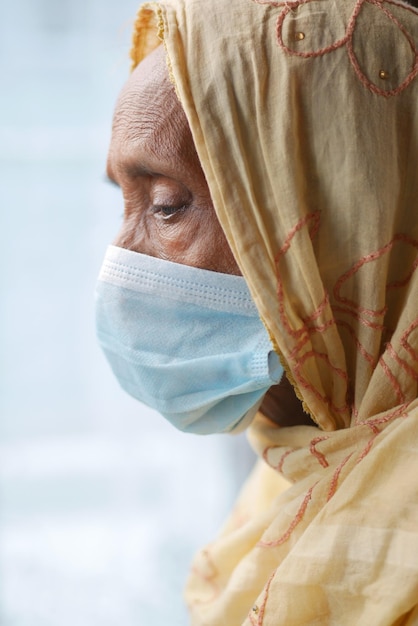 Porträt einer alten indischen Frau, die eine chirurgische Maske trägt