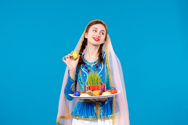 Porträt einer aserbaidschanischen Frau in traditioneller Kleidung mit xonca-blauer Wand Frühling Novruz ethnische Farbe