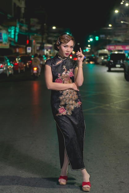 Porträt einer asiatischen Frau in schwarzem Kleid auf der Straße in der Nachtszene der Innenstadt, Nahaufnahme eines Mädchen-Streetstyles