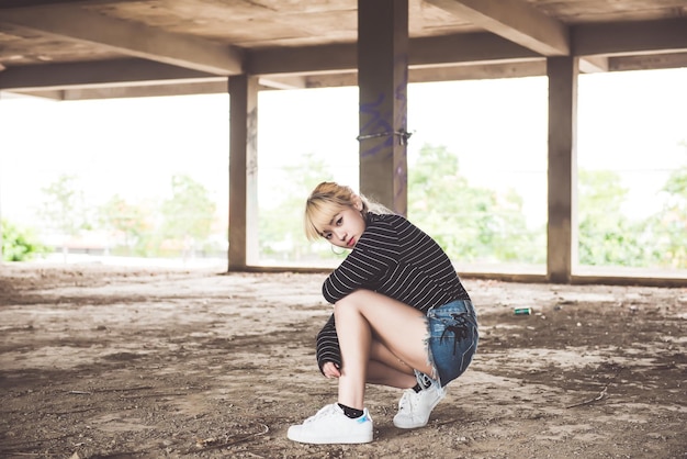 Porträt einer asiatischen Frau mit goldenen Haaren im verlassenen GebäudeLebensstil der modernen FrauVintage-Stildunkler Tonkawaii-Stilkurzer Denim