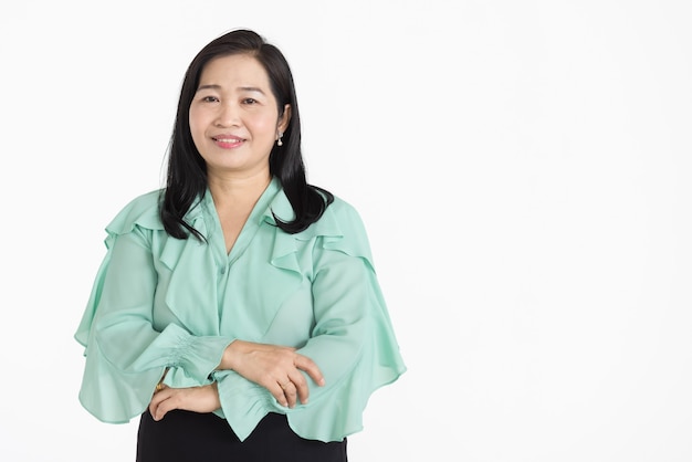 Porträt einer asiatischen Frau mittleren Alters, die eine mintgrüne Bluse trägt, die ordentlich lächelt und selbstbewusst isoliert aussieht.