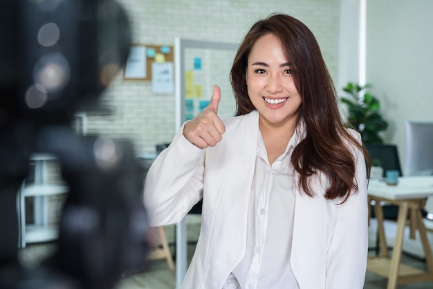 Porträt einer asiatischen Geschäftsfrau mit Daumen nach oben wie beim Aufnehmen von Videos für sozialen Einfluss