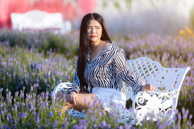 Porträt einer asiatischen jungen Frau, die einen glücklichen Reisenden mit schwarz-weißem Musterkleid genießt, das auf einem weiß blühenden Blumenfeld im Naturgarten von Thailandtravel Entspannungsurlaub genießt