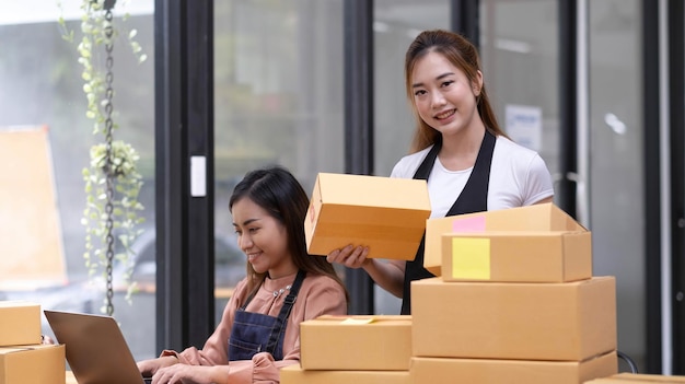 Porträt einer asiatischen jungen Frau, die zu Hause mit einer Kiste arbeitet, der Arbeitsplatz, der Kleinunternehmer, ein Kleinunternehmer, ein KMU oder ein freiberufliches Online- und Lieferkonzept