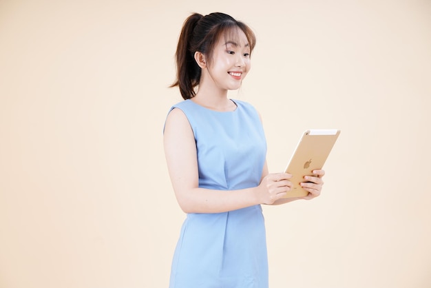 Porträt einer asiatischen jungen schönen und fröhlichen Frau, die ein Smartphone verwendet, das auf dem Hintergrund isoliert ist