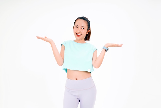 Porträt einer asiatischen jungen schönen und fröhlichen Frau im Fitness-Workout-Outfit mit Fingerzeig auf Kopienraum isoliert auf Hintergrund