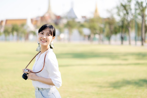 Foto porträt einer asiatischen reisenden mit kamera asien-sommertourismus-urlaubskonzept mit dem großen palast im hintergrund in bangkok thailand