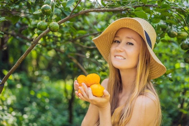 Porträt einer attraktiven Bäuerin erntet Orange im Bio-Bauernhof Fröhliches Mädchen in Glücksgefühlen beim Ernten von Orangen im Garten Landwirtschafts- und Plantagenkonzept