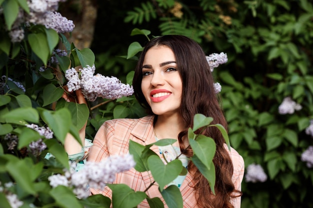 Porträt einer attraktiven brünetten Frau zwischen lila Blumen im Frühling