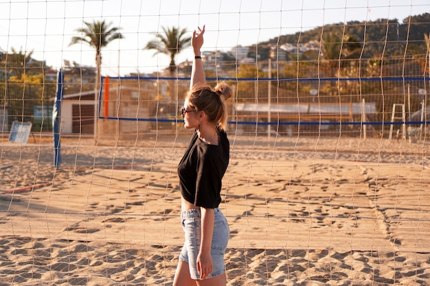 Porträt einer attraktiven Frau in der Nähe von Volleyballnetz am Strand