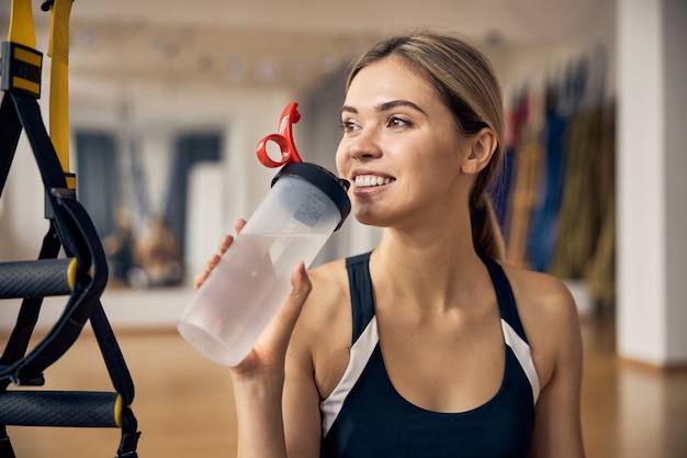 Porträt einer attraktiven jungen Frau mit einem glücklichen Lächeln, die in einem Fitnessstudio steht