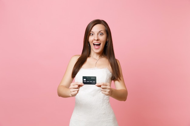 Porträt einer aufgeregten Frau im weißen Kleid mit Kreditkarte credit
