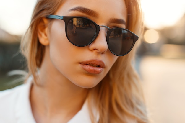 Porträt einer bezaubernden jungen Frau mit den sexy Lippen in der schwarzen stilvollen Sonnenbrille
