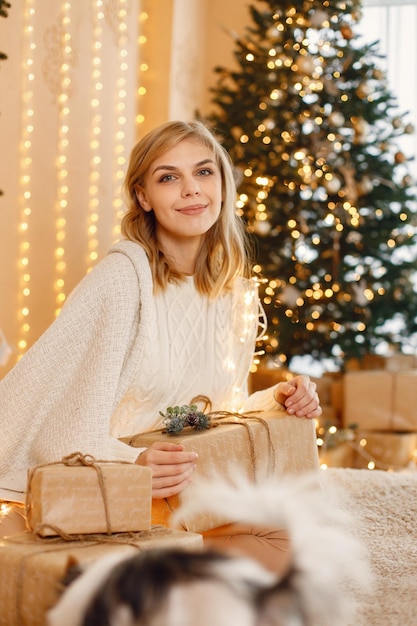 Porträt einer blonden Frau, die nahe Weihnachtsbaum sitzt