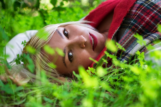 Porträt einer blonden Frau, die zwischen den Waldklee liegt.
