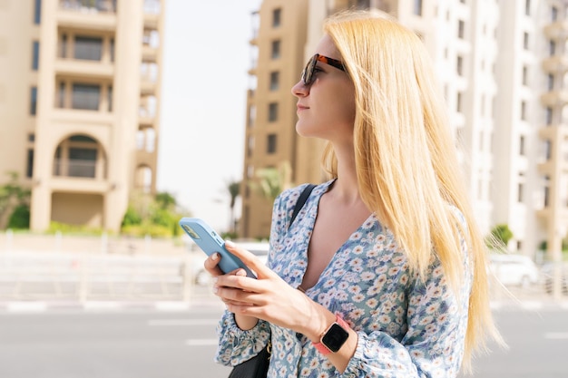 Porträt einer Blondine mit Handy vor dem Hintergrund urbaner Landschaften