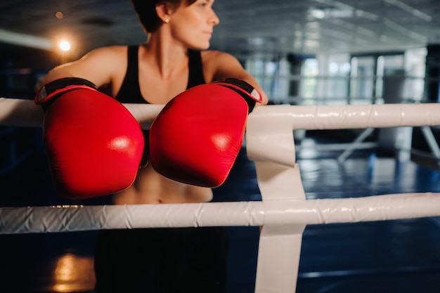 Porträt einer Boxerin in roten Handschuhen im Fitnessstudio während des Trainings.