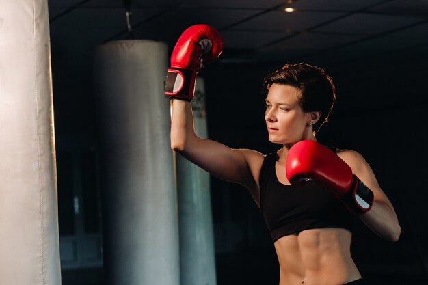 Porträt einer Boxerin in roten Handschuhen im Fitnessstudio während des Trainings