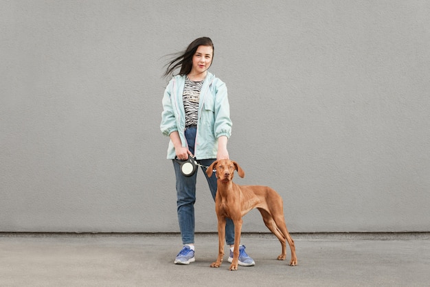 Porträt einer brünetten Frau mit einem Hund an der Leine steht