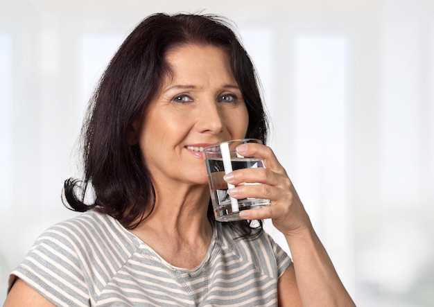 Porträt einer brünetten Frau trinkt Wasser aus Glas