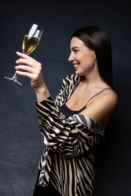 Porträt einer Brünetten in schickem Hemd und Hose mit einem Glas Champagner