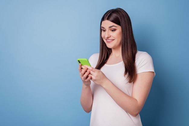 Porträt einer charmanten, aufgeregten hübschen Dame mit einem zahnigen Lächeln auf dem Handy-Look auf blauem Hintergrund