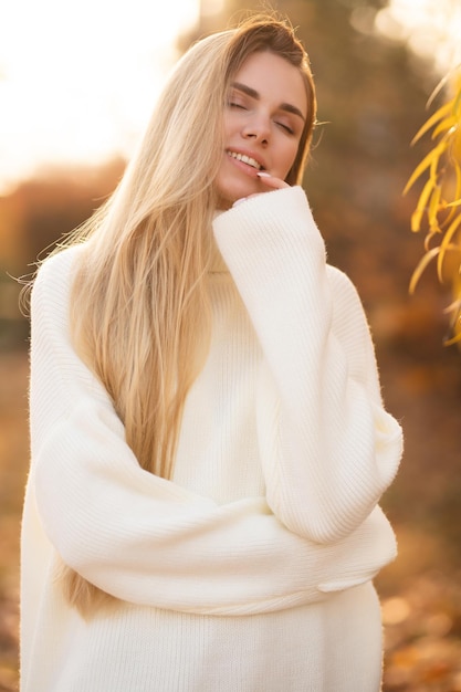 Porträt einer charmanten Blondine mit einem wunderschönen Lächeln Ein Mädchen in einem weißen Pullover entspannt sich