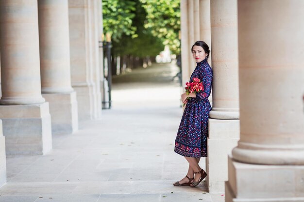 Porträt einer eleganten Frau in einem blauen Kleid, die neben einem Stadtgebäude posiert