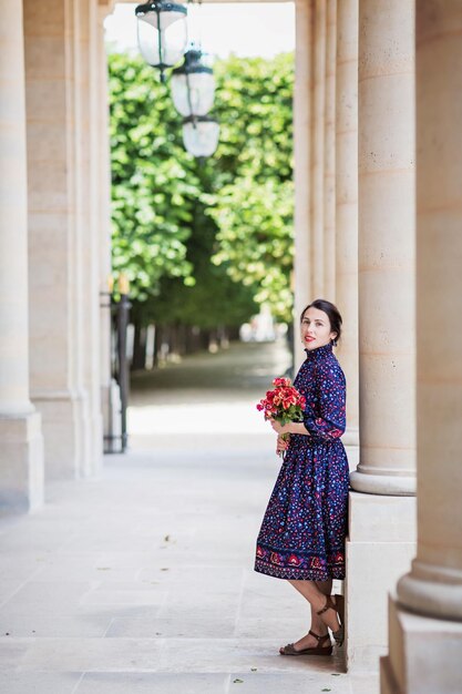 Porträt einer eleganten Frau in einem blauen Kleid, die neben einem Stadtgebäude posiert