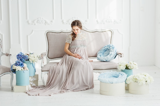 Porträt einer eleganten schönen schwangeren Frau, die graues Kleid trägt