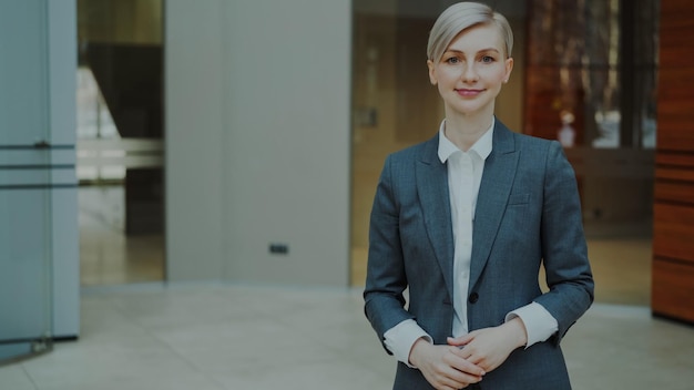 Porträt einer erfolgreichen blonden Geschäftsfrau, die in einem modernen Büro lächelt und in die Kamera blickt