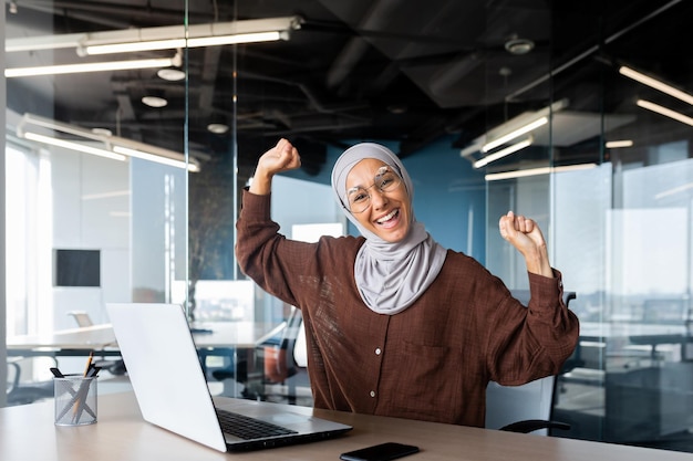 Porträt einer erfolgreichen Geschäftsfrau in Hijab-Muslimin, die im Büro mit Laptop arbeitet