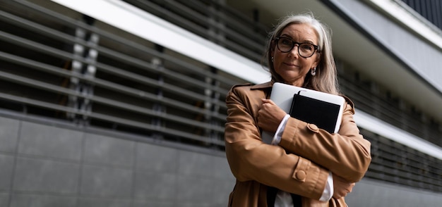 Porträt einer erfolgreichen, reifen Geschäftsfrau mit einem Laptop in der Hand außerhalb des Büros