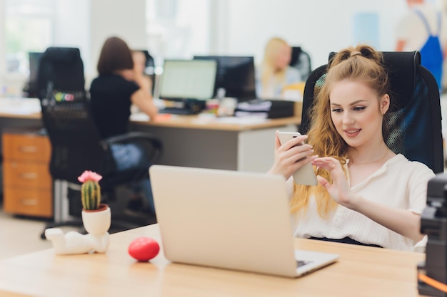 Porträt einer ernsthaften Geschäftsfrau, die im Büro einen Laptop benutzt. Schöne Hipster-Frau, die sich im modernen Büro Notizen macht