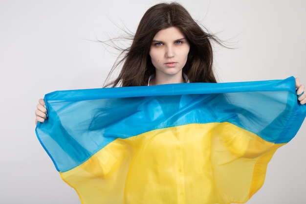 Porträt einer ernsthaften ukrainischen Frau mit blauer und gelber ukrainischer Flagge auf weißem Hintergrund