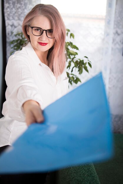 Porträt einer erwachsenen Unternehmerin mit gräulichen Haaren in einer Führungsposition, gekleidet in eine weiße Bluse und beschäftigt im Büro zu arbeiten