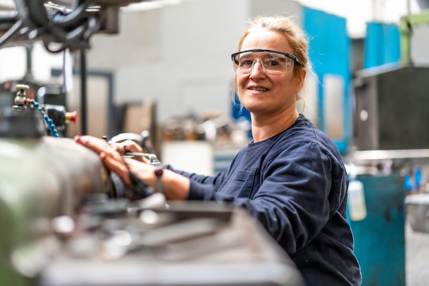 Foto porträt einer fabrikarbeiterin, die im kontrollbereich einer metallfräsmaschine in einer industriefabrik arbeitet