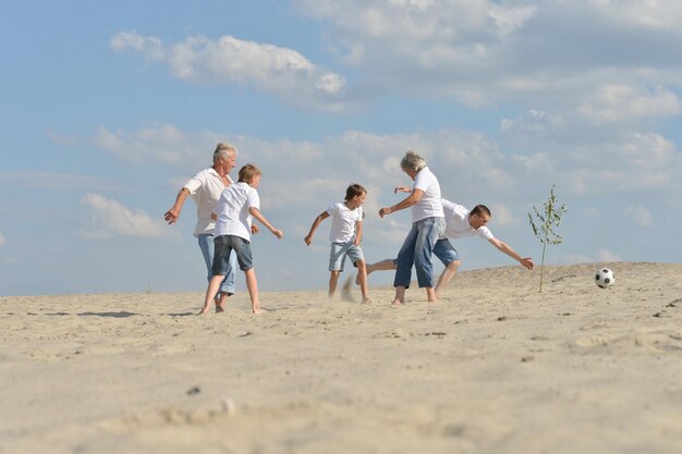 Porträt einer Familie, die im Sommer am Strand Fußball spielt