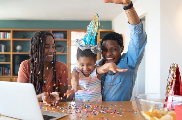 Porträt einer Familie, die online Geburtstag auf einem Videoanruf mit Laptop feiert, während zu Hause bleiben.