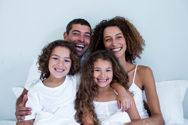 Porträt einer Familie, die zusammen auf Bett sitzt