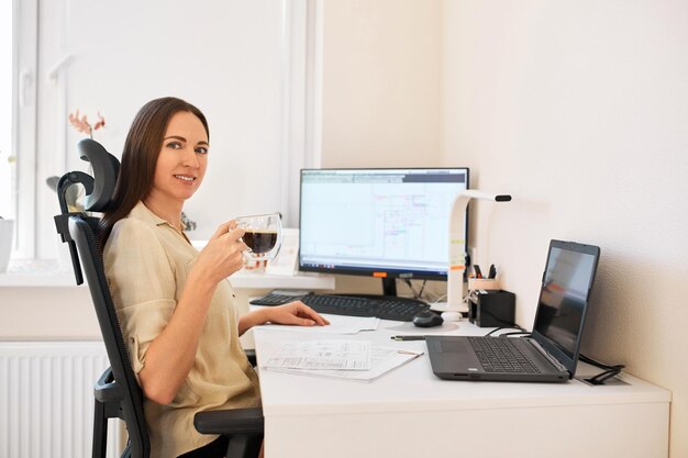 Foto porträt einer fernarbeiterin eine schöne frau sitzt an einem tisch. selbstbewusste freiberuflerin, die von zu hause aus arbeitet