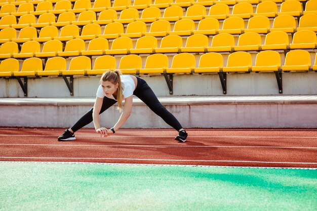 Porträt einer Fitnessfrau, die Aufwärmübungen am Stadion macht