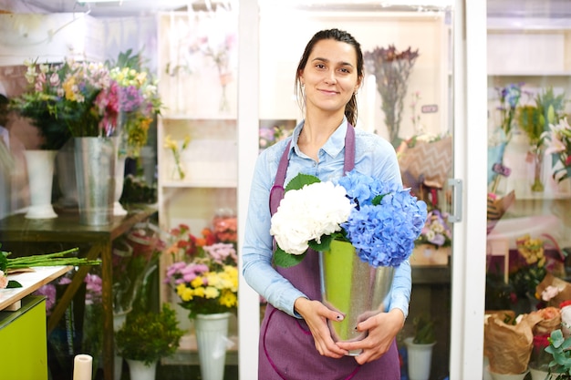 Porträt einer Floristin in der Werkstatt auf dem Hintergrund von Schaufenstern mit Blumen