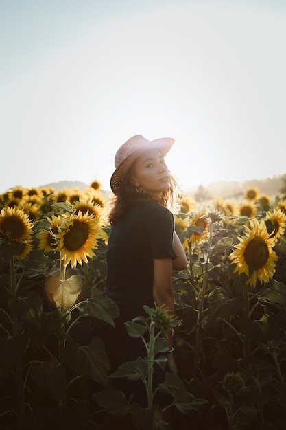 Porträt einer Frau, die an Sonnenblumenpflanzen gegen den Himmel steht