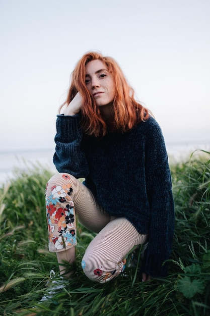Porträt einer Frau, die auf dem Feld gegen den Himmel knient