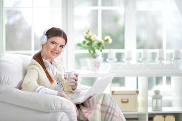 Porträt einer Frau, die auf dem Sofa Musik hört