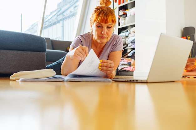 Porträt einer Frau, die auf einem Parkettboden mit Laptop-Notebooks und Emotionen im Gesicht liegt