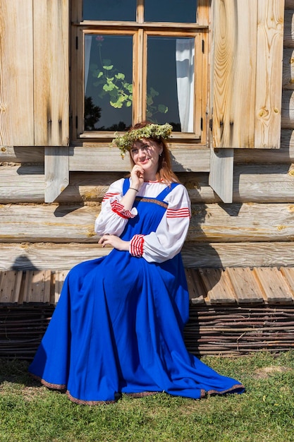 Foto porträt einer frau, die auf einem sitz gegen ein holzhaus sitzt