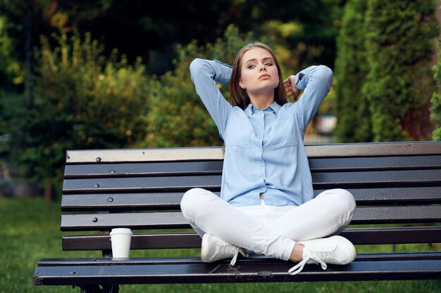 Foto porträt einer frau, die auf einer bank im park sitzt