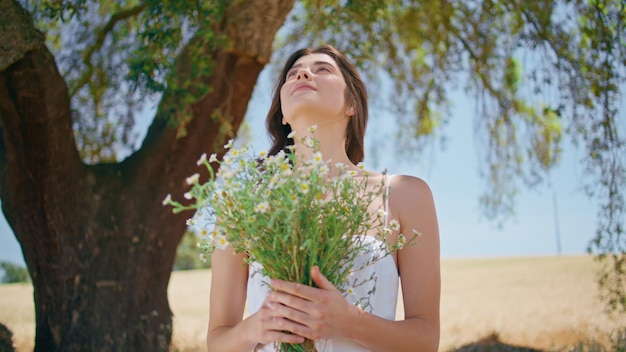 Porträt einer Frau, die Blumen in ländlicher Natur umarmt, schöne lächelnde Dame